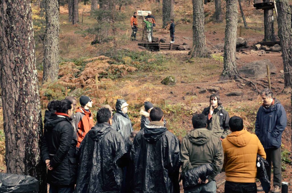 Grupo de personas en actividad de formación de team building al aire libre mostrando resiliencia por las condiciones de mal clima que hay.