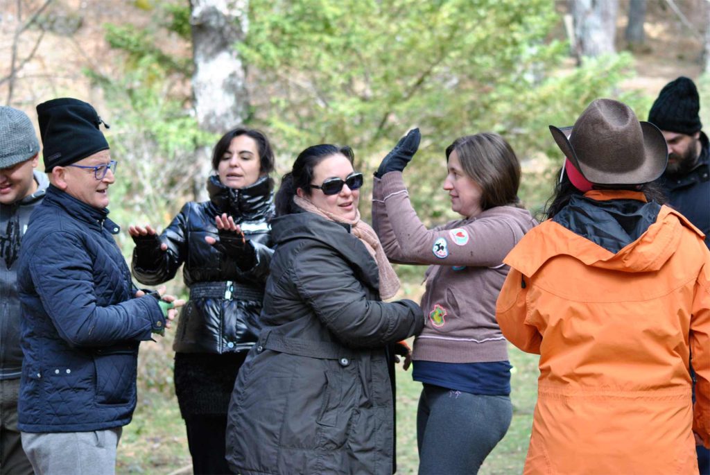 Equipo de personas de empresa en programa de team building para mejorar la toma de decisiones celebrando la cohesión de equipo