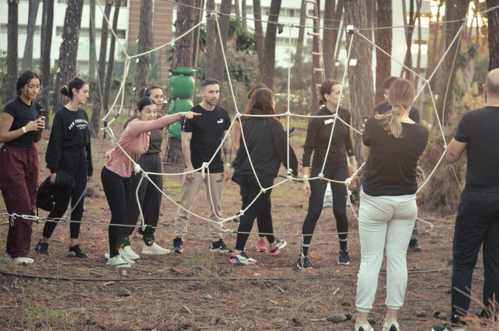 Equipo de empresa enfrentando desafío de la Tela de araña en programa de Team Building al aire libre